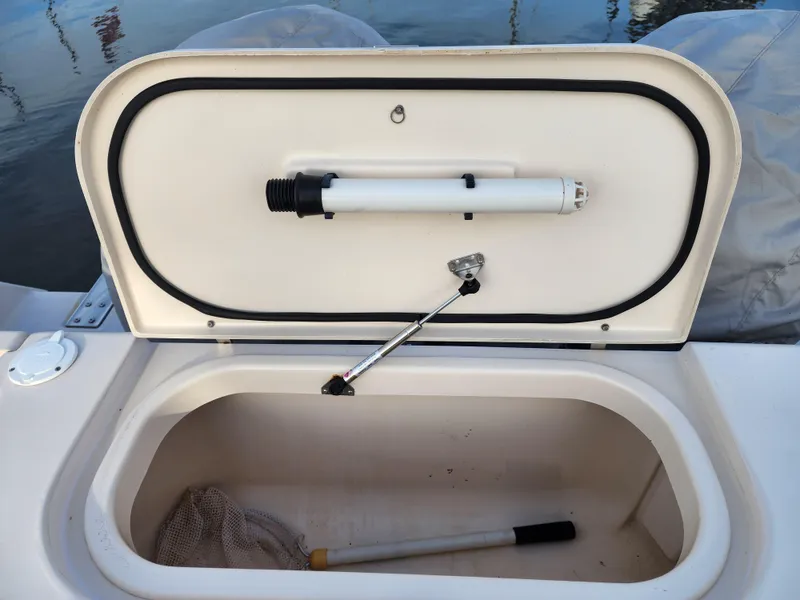 Slide: The Image of Open storage compartment on 2005 Grady-White Bimini 306 boat, featuring a net and handle. - 25