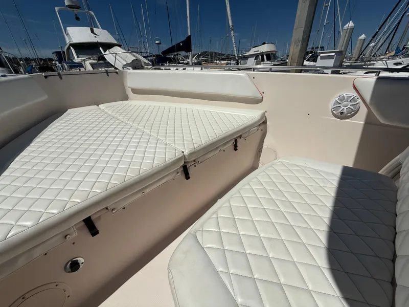 Slide: The Image of 2005 Grady-White Bimini 306 boat interior with white cushioned seating in a marina. - 7