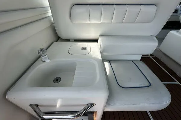 Slide: The Image of 1996 Sea Ray 400 Express Cruiser interior with white seating and sink. - 24