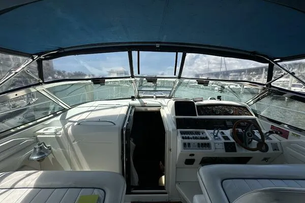 Slide: The Image of 1996 Sea Ray 400 Express Cruiser cockpit with steering wheel and control panel, docked at marina. - 48