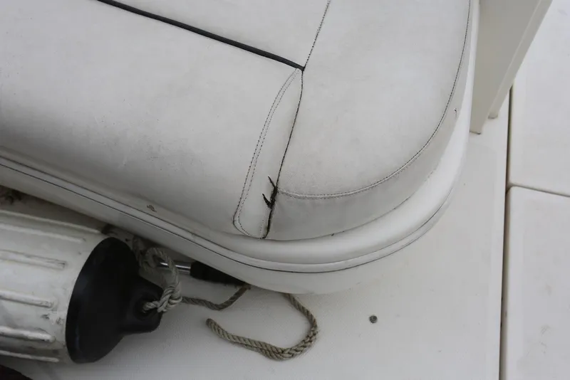 Slide: The Image of White leather seat with visible tear on a 2003 Sea Ray 420 Sundancer boat. - 17
