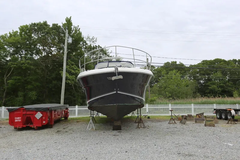 Slide: The Image of 2003 Sea Ray 420 Sundancer yacht on stands, surrounded by trees and a white fence. - 2