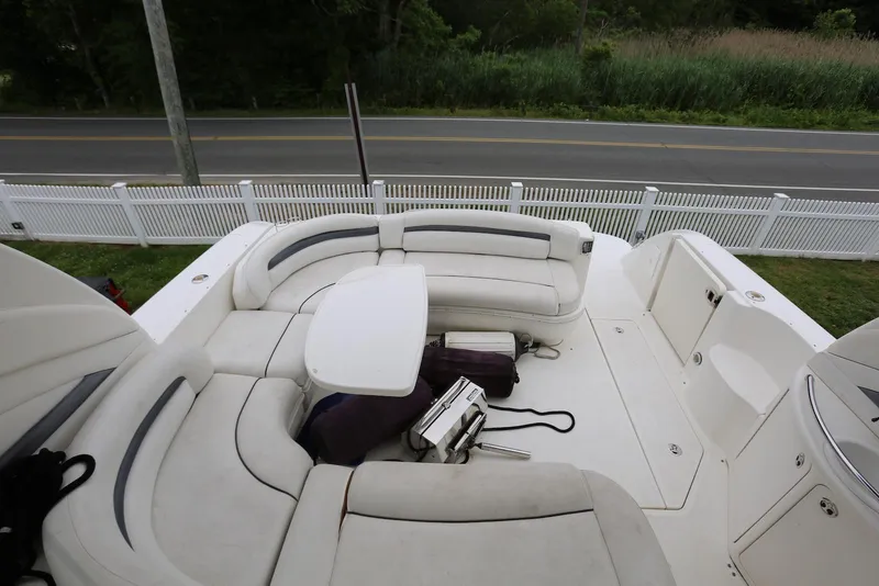 Slide: The Image of 2003 Sea Ray 420 Sundancer boat with white seating and table, near a road and fence. - 24