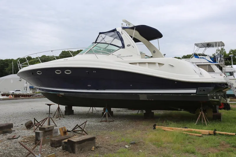 Slide: The Image of 2003 Sea Ray 420 Sundancer yacht on dry dock, blue and white hull, overcast sky. - 4