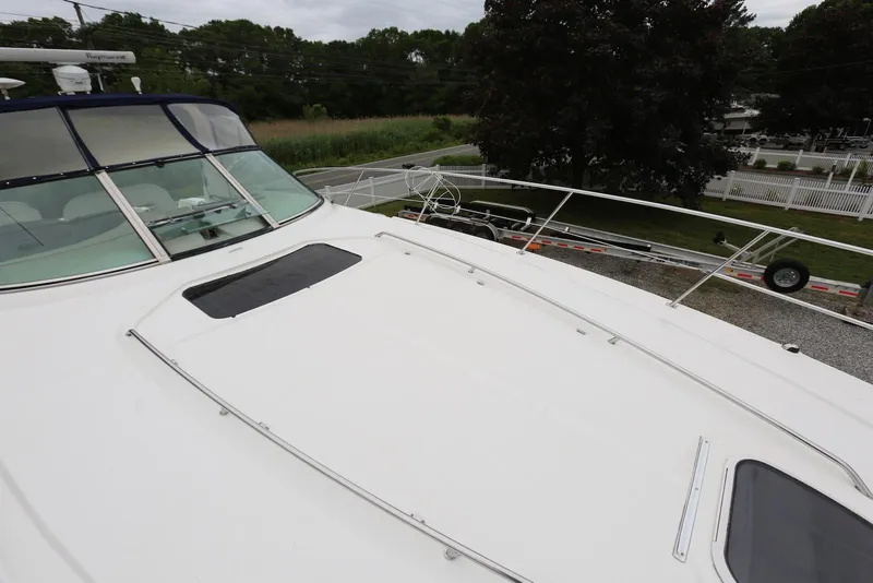 Slide: The Image of 2003 Sea Ray 420 Sundancer yacht deck with windshield, docked near greenery. - 42