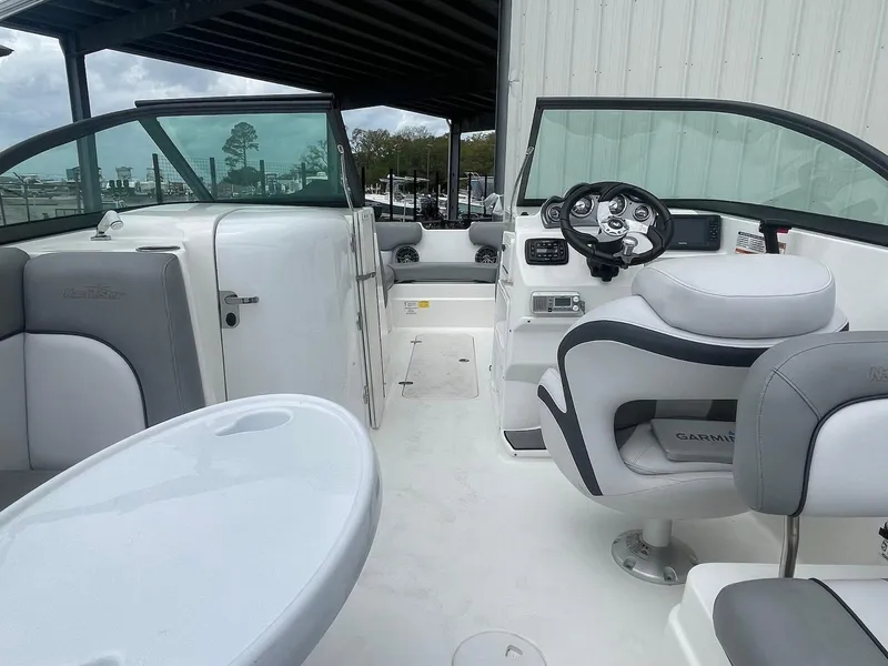 Slide: The Image of 2021 NauticStar 223 DC boat interior with seating, steering wheel, and table. - 4