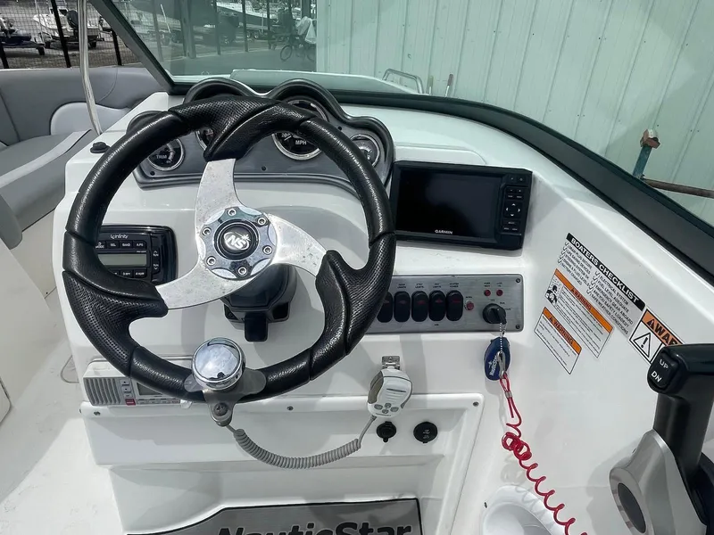Slide: The Image of 2021 NauticStar 223 DC boat dashboard with steering wheel and control panel. - 5
