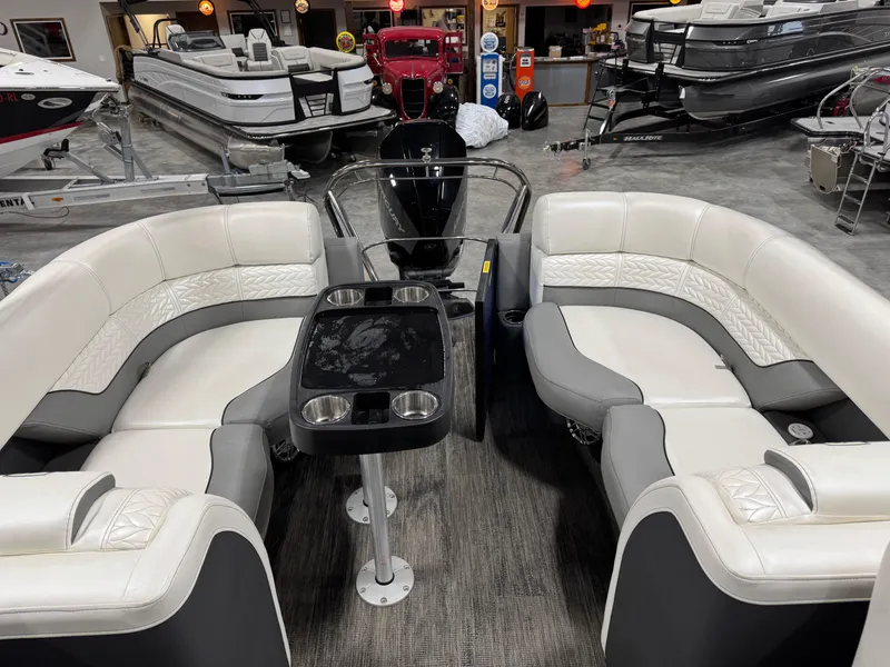 Slide: The Image of 2020 Godfrey 250 Monaco pontoon boat interior with plush seating and table in showroom. - 10