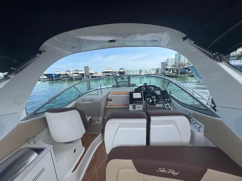Slide: The Image of 2008 Sea Ray 330 Sundancer interior view at marina, showcasing helm and seating area. - 8