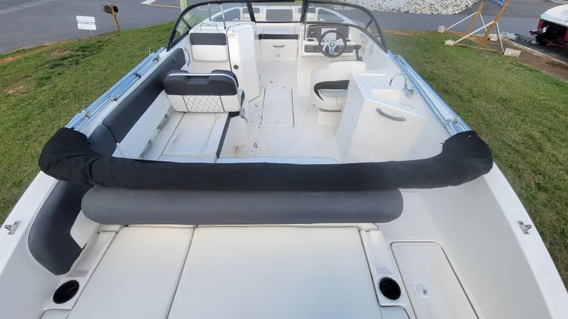 Slide: The Image of 2021 Bayliner DX 2200 boat interior with seating and steering wheel, parked on grass. - 10