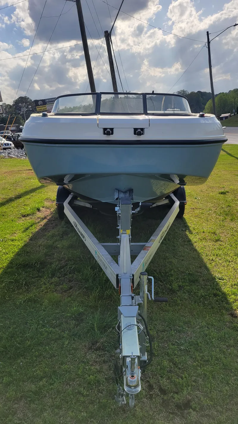 Slide: The Image of 2021 Bayliner DX 2200 boat on trailer, parked on grass under cloudy sky. - 3