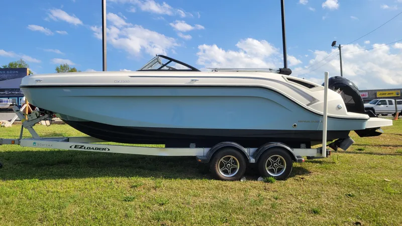Slide: The Image of 2021 Bayliner DX 2200 boat on trailer under blue sky. - 4