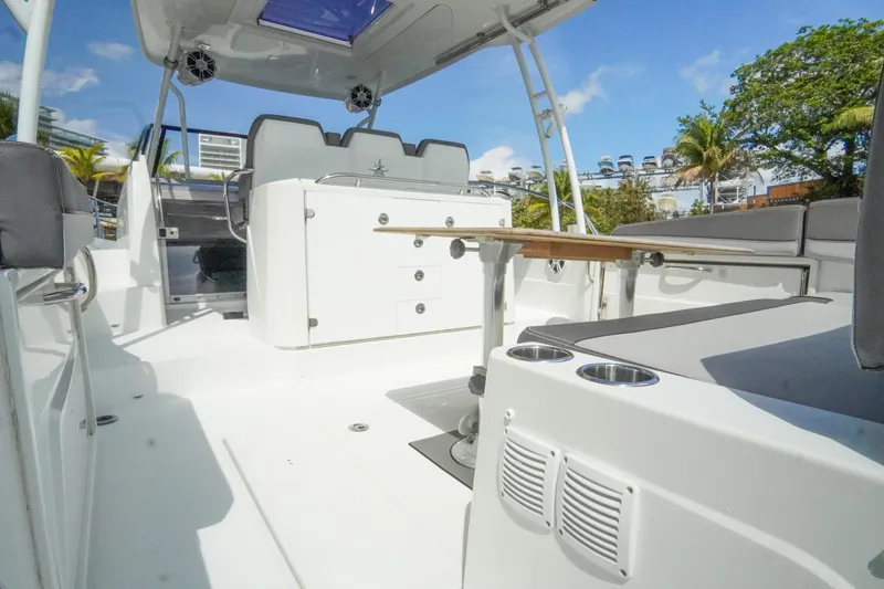 Slide: The Image of 2021 Jeanneau Leader 10.5 WA boat interior with seating and table, under clear blue sky. - 17