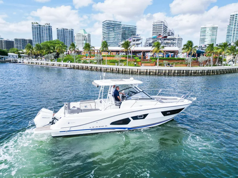 Slide: The Image of 2021 Jeanneau Leader 10.5 WA boat cruising near urban waterfront with modern buildings. - 2