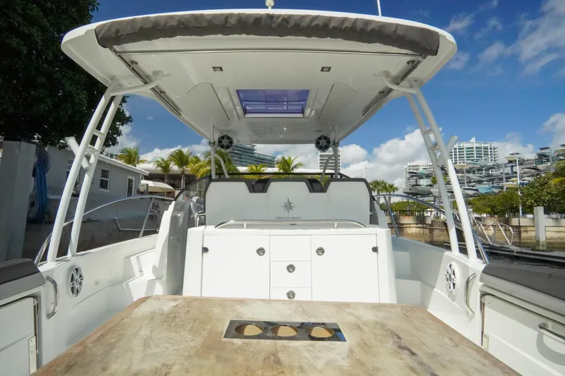 Slide: The Image of 2021 Jeanneau Leader 10.5 WA boat interior with table, canopy, and urban backdrop. - 32