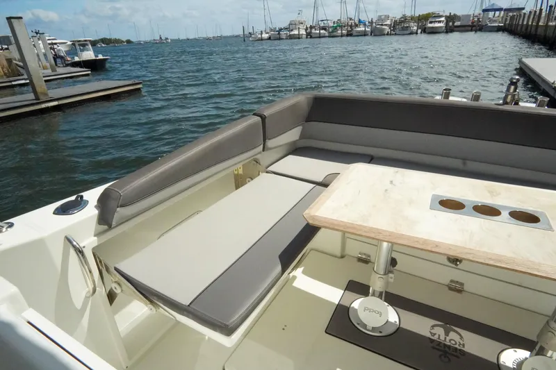 Slide: The Image of 2021 Jeanneau Leader 10.5 WA boat with spacious seating and table, docked by the water. - 46