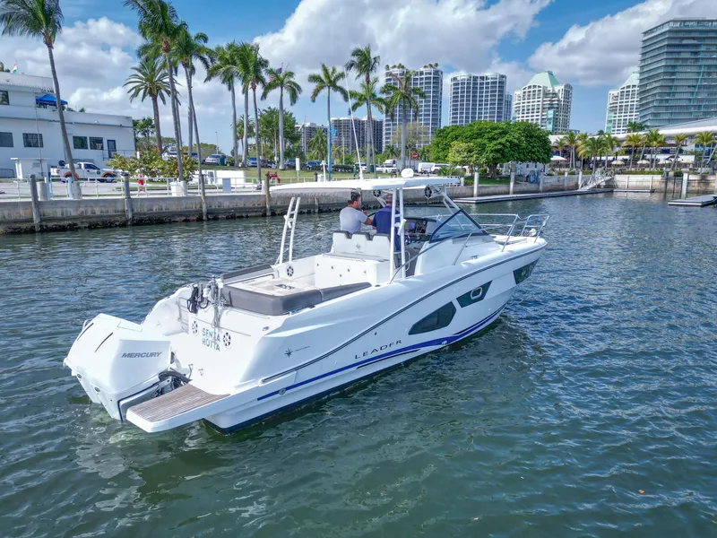 Slide: The Image of 2021 Jeanneau Leader 10.5 WA boat cruising in a marina with palm trees and buildings. - 7