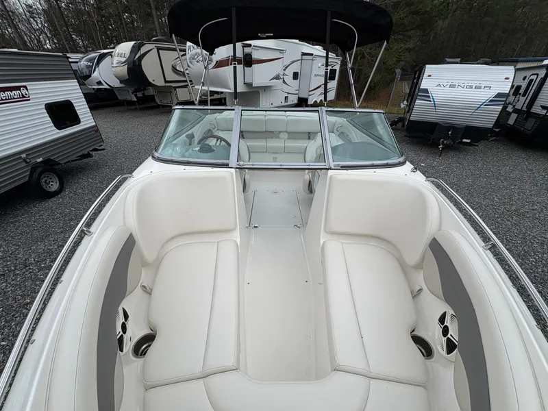 Slide: The Image of 2009 Chaparral 210 SSi boat with white interior, parked among RVs and trailers. - 23