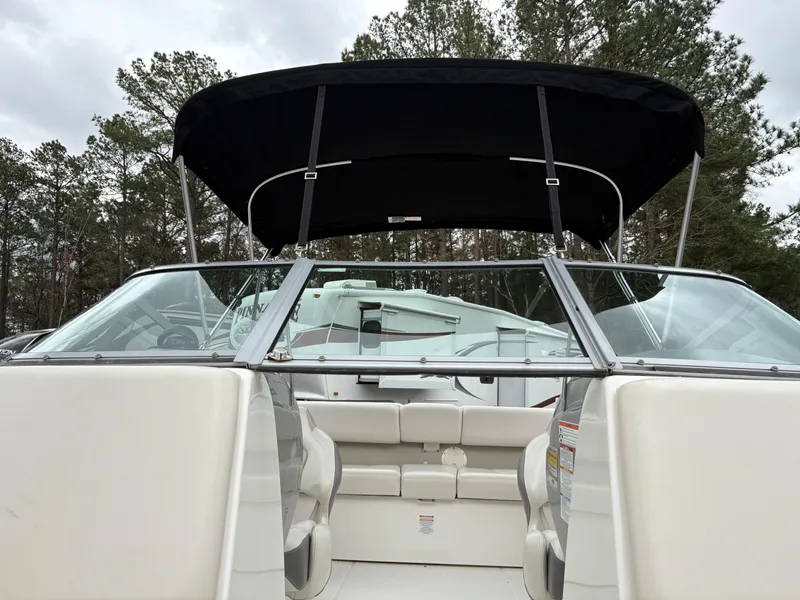 Slide: The Image of 2009 Chaparral 210 SSi boat with canopy, white interior, and forest backdrop. - 24