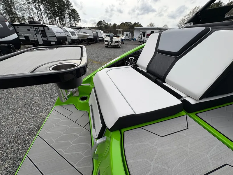 Slide: The Image of 2022 Yamaha Boats 255XD interior with sleek seating and table, parked near RVs. - 11