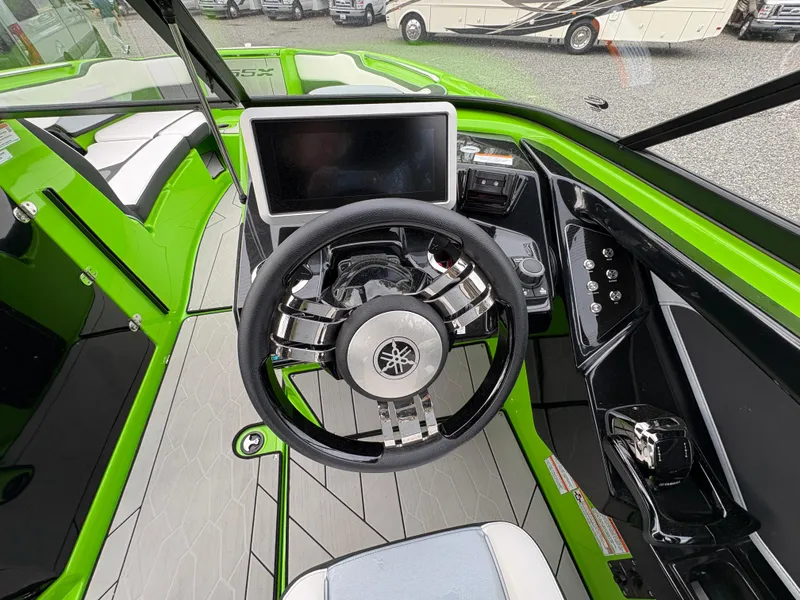 Slide: The Image of 2022 Yamaha Boats 255XD cockpit with steering wheel and touchscreen display, featuring vibrant green accents. - 19