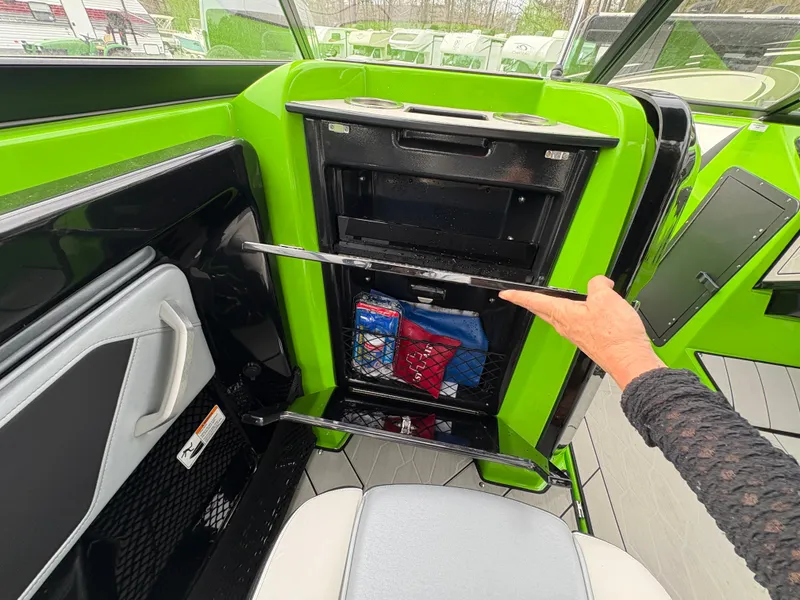 Slide: The Image of 2022 Yamaha Boats 255XD interior storage compartment with vibrant green accents and organized gear. - 30