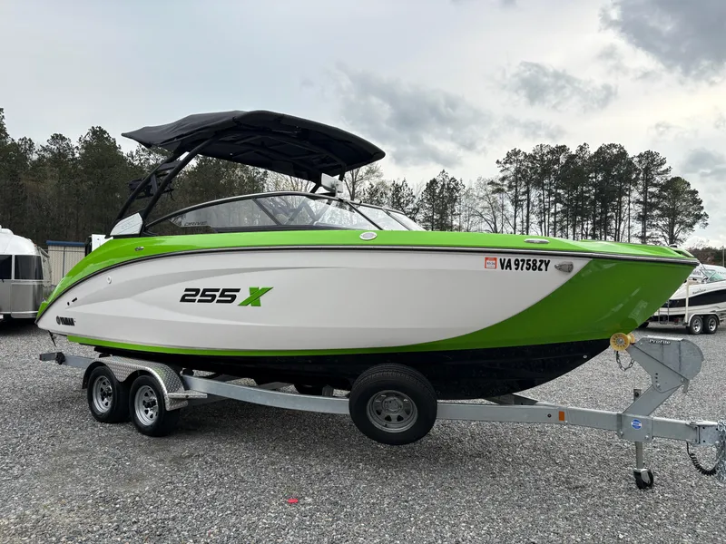 Slide: The Image of 2022 Yamaha Boats 255XD in green and white on a trailer, parked outdoors. - 6
