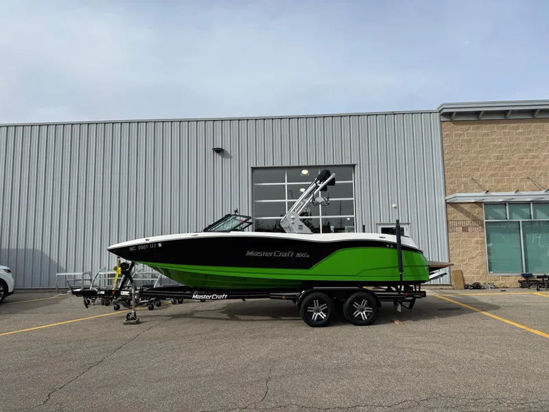 Slide: The Image of 2019 MasterCraft NXT22 boat on trailer, parked outside industrial building. - 1