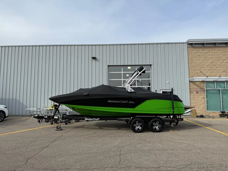 Slide: The Image of 2019 MasterCraft NXT22 boat with cover, parked on trailer outside industrial building. - 19