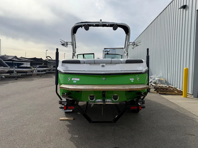 Slide: The Image of 2019 MasterCraft NXT22 boat, green and white, parked outdoors near a metal building. - 4