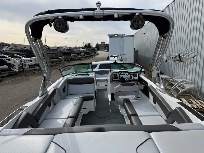 Slide: The Image of 2019 MasterCraft NXT22 boat interior with seating and steering wheel, parked outdoors. - 7