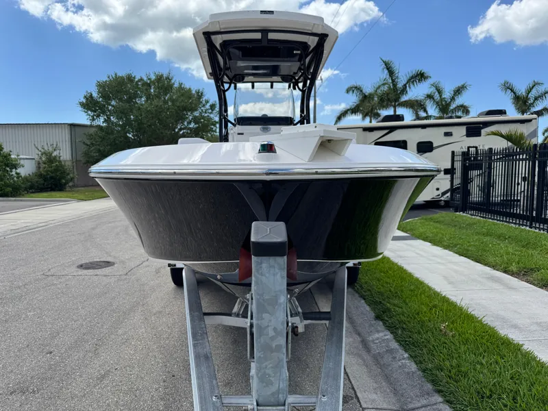 Slide: The Image of 2016 Wellcraft 241 boat on trailer, parked on street with palm trees and RV in background. - 19