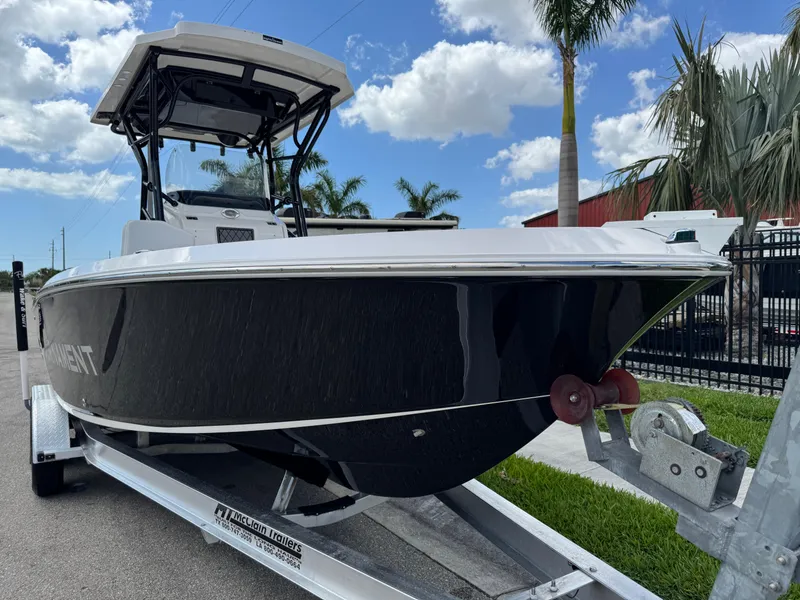 Slide: The Image of 2016 Wellcraft 241 boat on trailer, black hull, palm trees, blue sky background. - 20