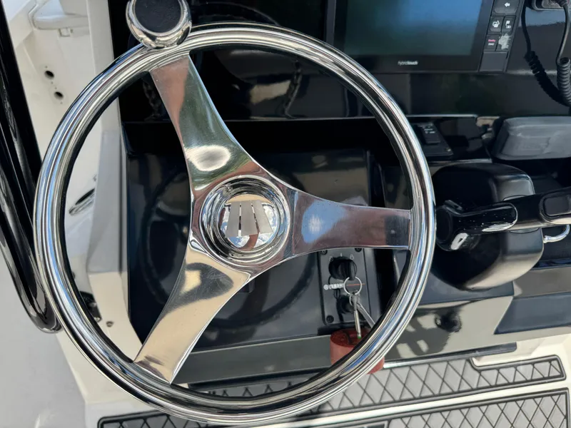 Slide: The Image of Steering wheel and controls of a 2016 Wellcraft 241 boat. - 31