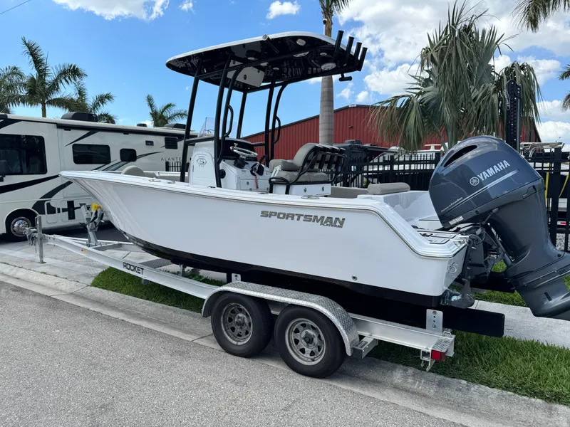 Slide: The Image of 2023 Sportsman Open 212 Center Console boat on trailer, parked near palm trees. - 3