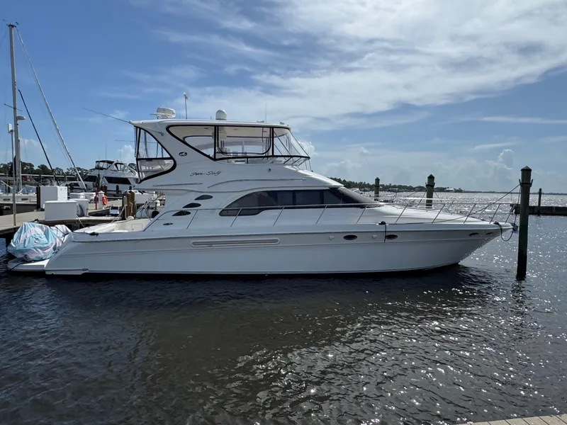 Slide: The Image of 2004 Sea Ray 560 Sedan Bridge yacht docked at marina under a partly cloudy sky. - 1
