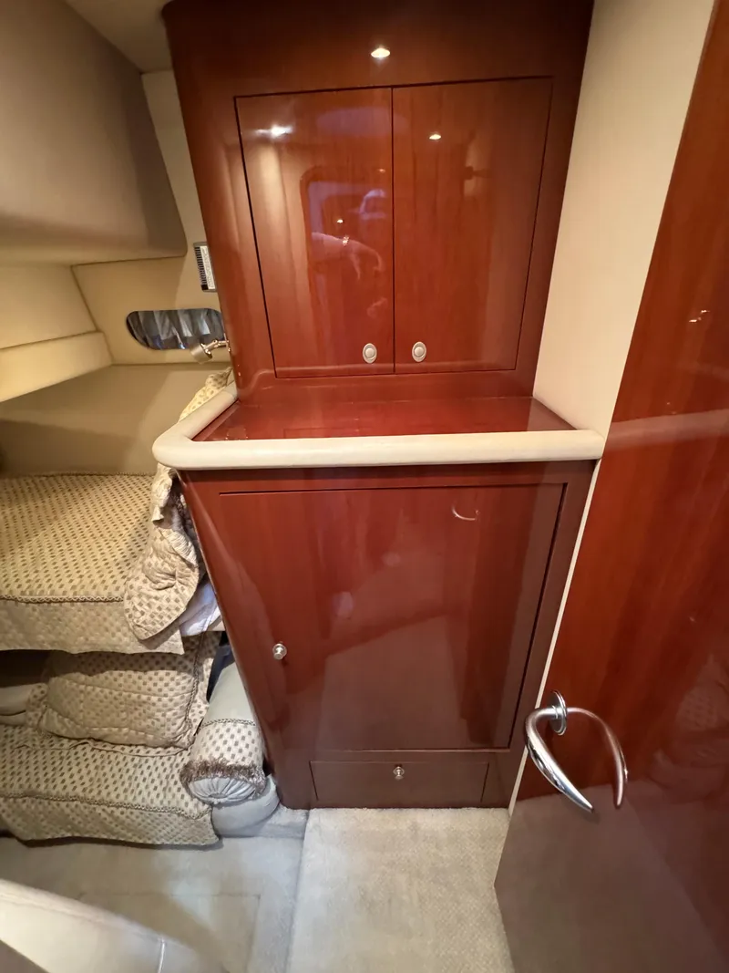 Slide: The Image of Interior of 2004 Sea Ray 560 Sedan Bridge with wooden cabinetry and cozy bedding. - 25