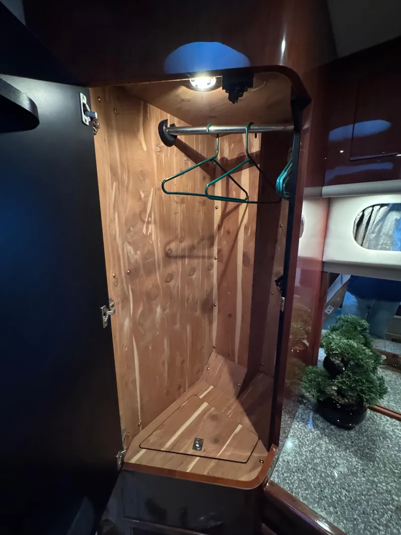 Slide: The Image of 2004 Sea Ray 560 Sedan Bridge wooden closet interior with hangers and lighting. - 27