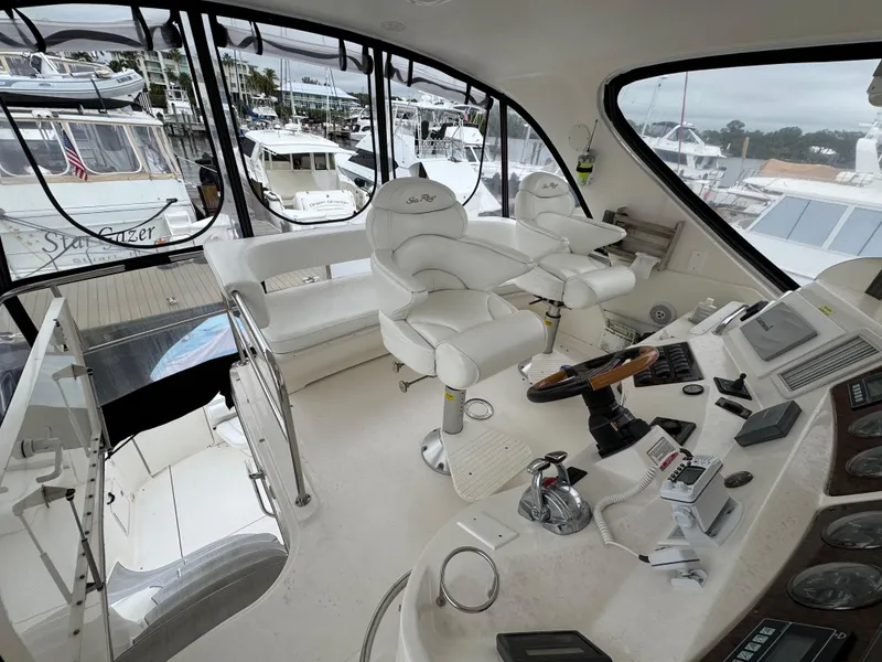 Slide: The Image of 2004 Sea Ray 560 Sedan Bridge helm with white leather seats and control panel. - 28