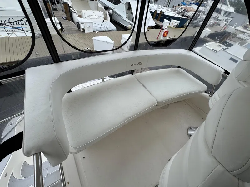 Slide: The Image of 2004 Sea Ray 560 Sedan Bridge interior with white seating and marina view. - 31