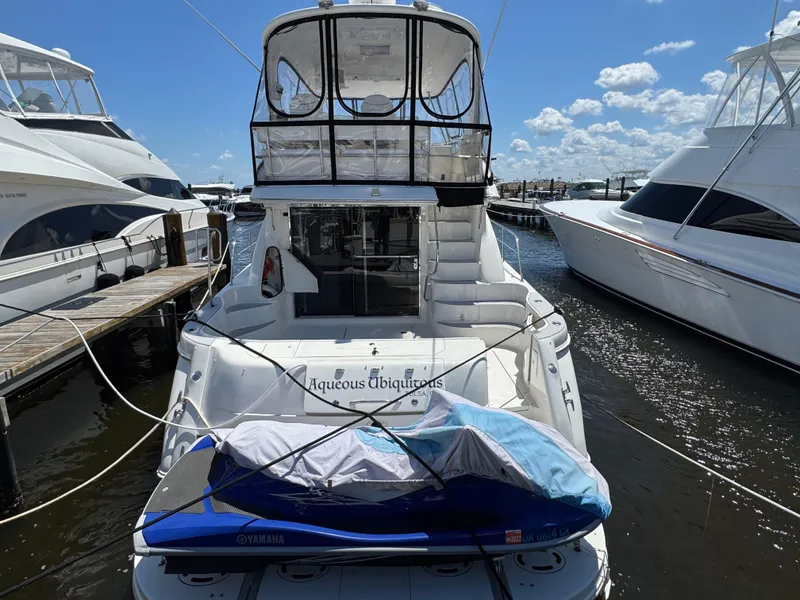Slide: The Image of 2004 Sea Ray 560 Sedan Bridge yacht docked with jet ski, under clear blue sky. - 4