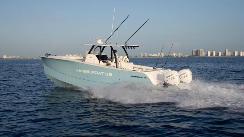 Slide: The Image of 2025 Hammer Yachts HammerCat 35 cruising on open water, city skyline in background. - 2