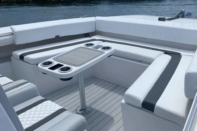 Slide: The Image of 2025 Hammer Yachts HammerCat 35 interior with white seating and table, docked by water. - 21