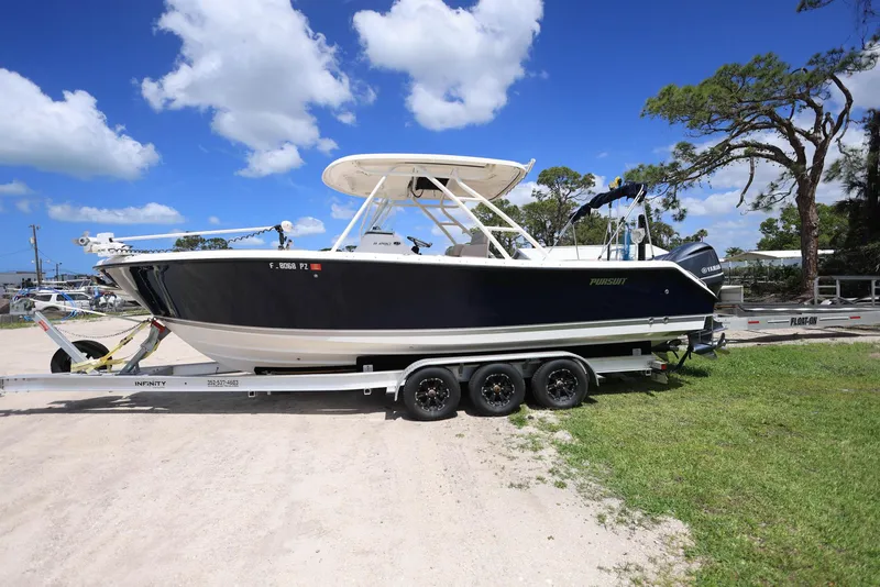 Slide: The Image of 2015 Pursuit S 280 Sport boat on a trailer, parked outdoors under a clear blue sky. - 0