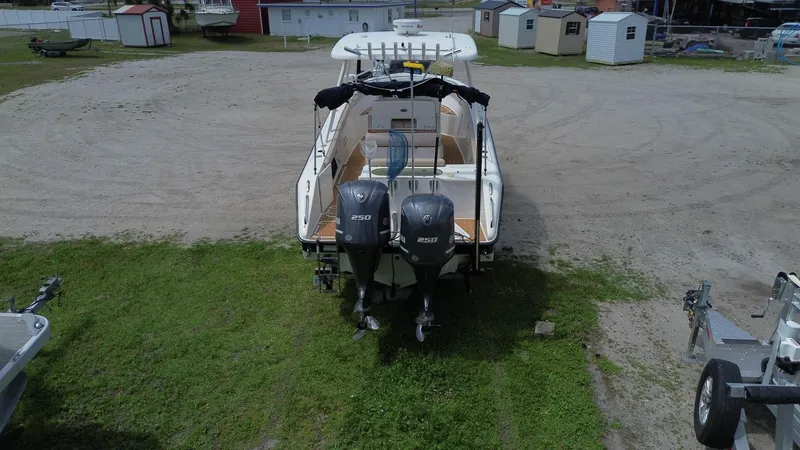 Slide: The Image of 2015 Pursuit S 280 Sport boat with dual outboard engines, parked on grass. - 10