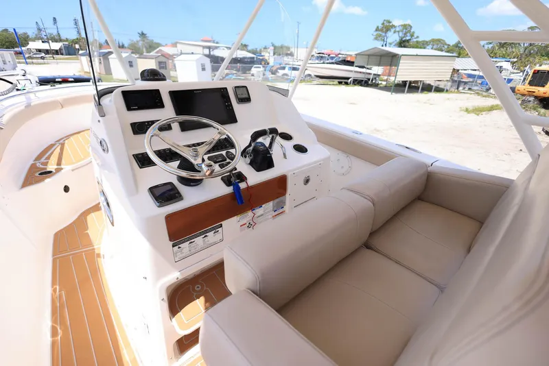 Slide: The Image of 2015 Pursuit S 280 Sport boat cockpit with steering wheel and beige seating. - 22