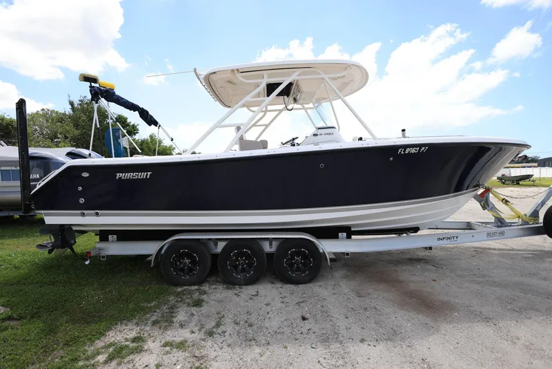 Slide: The Image of 2015 Pursuit S 280 Sport boat on a trailer, parked outdoors under a blue sky. - 4