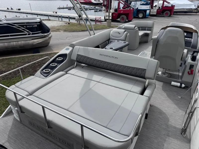 Slide: The Image of 2022 Bennington LX24FB pontoon boat with spacious seating and cup holders, docked by the water. - 6