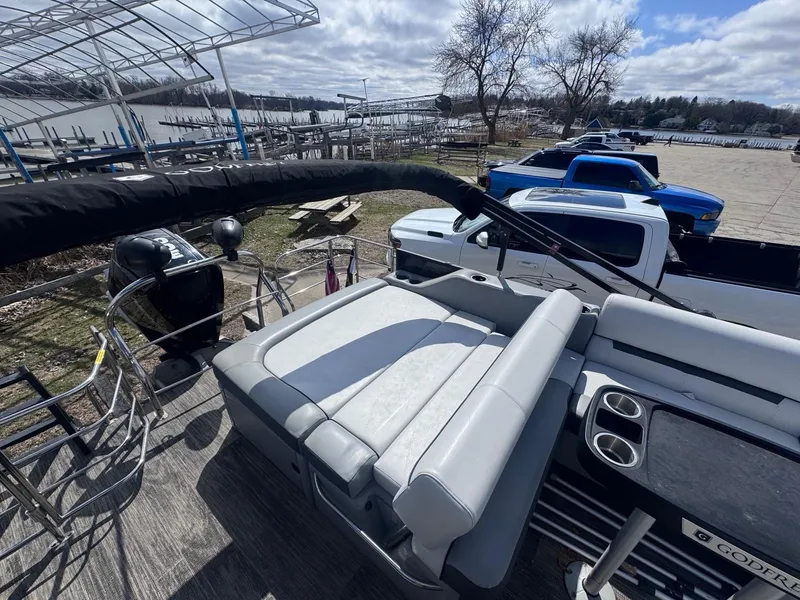 Slide: The Image of 2021 Sweetwater 2486SFL pontoon boat with seating, docked near a lake and parked trucks. - 10