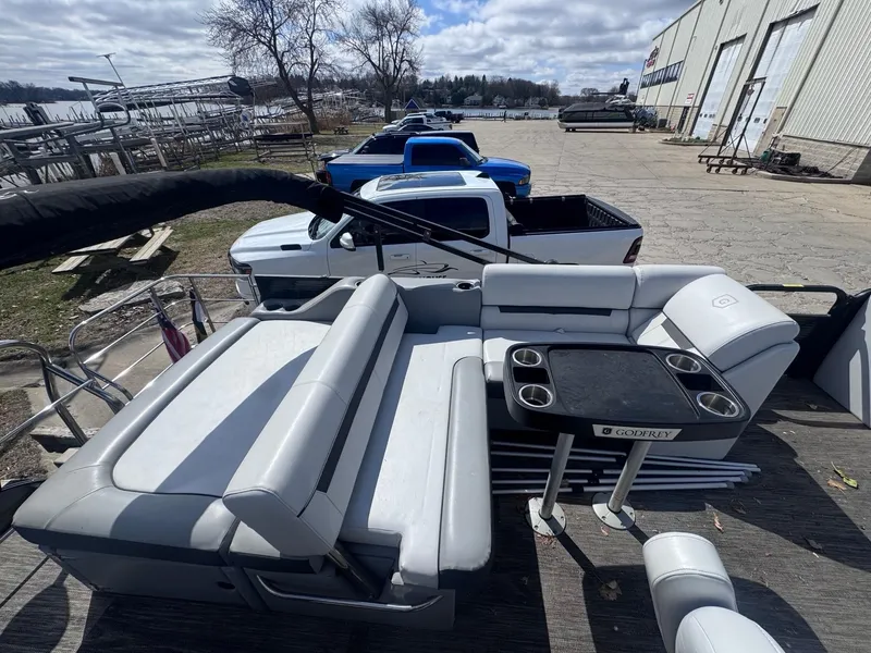 Slide: The Image of 2021 Sweetwater 2486SFL pontoon boat with seating and table, parked near a lake. - 11